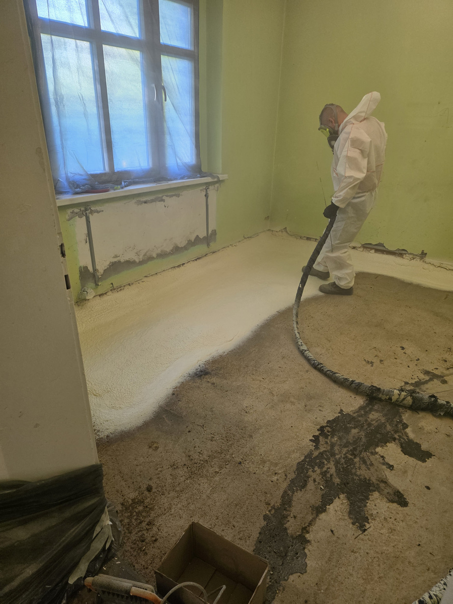 Aplikacja piany PUR pistoletem natryskowym na podłogę przy oknie